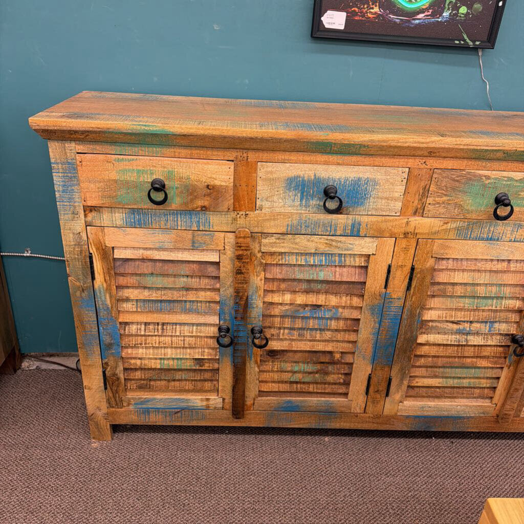 Wooden cabinet with distressed finish against a teal wall.