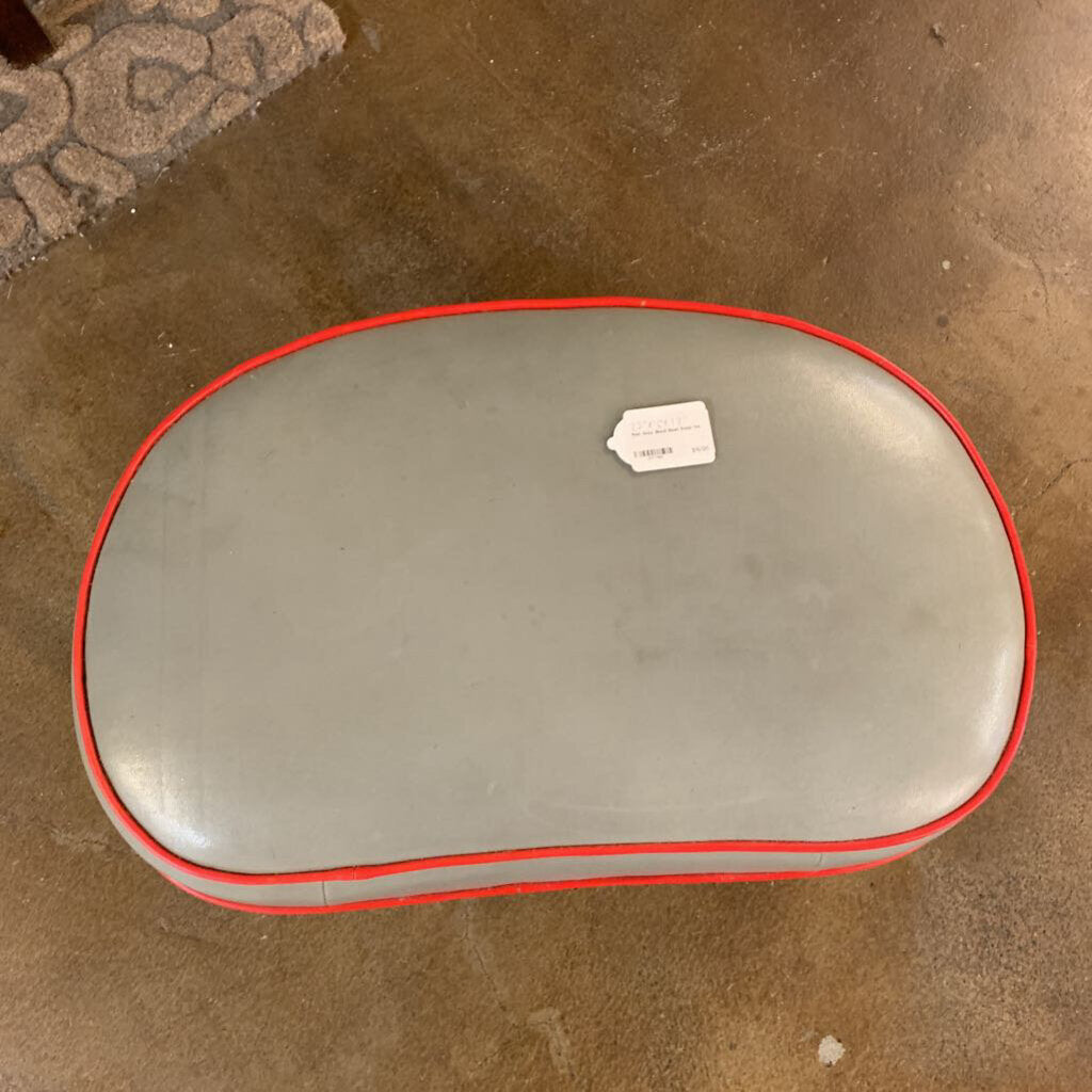 Gray cushion with red trim on a brown floor