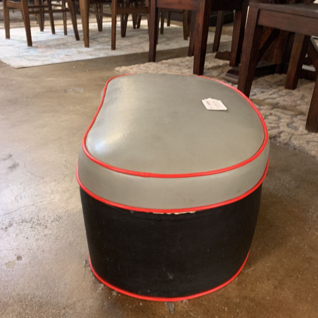 Round ottoman with gray top and black bottom on a concrete floor