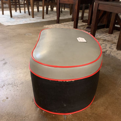 Round ottoman with gray top and black bottom on a concrete floor