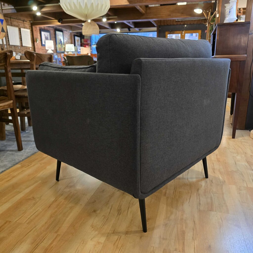 Gray armchair on a wooden floor with a restaurant interior in the background