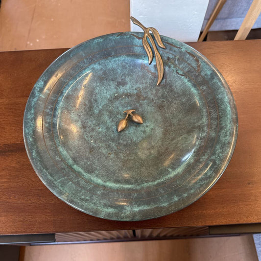 Bronze plate with decorative elements on a wooden surface