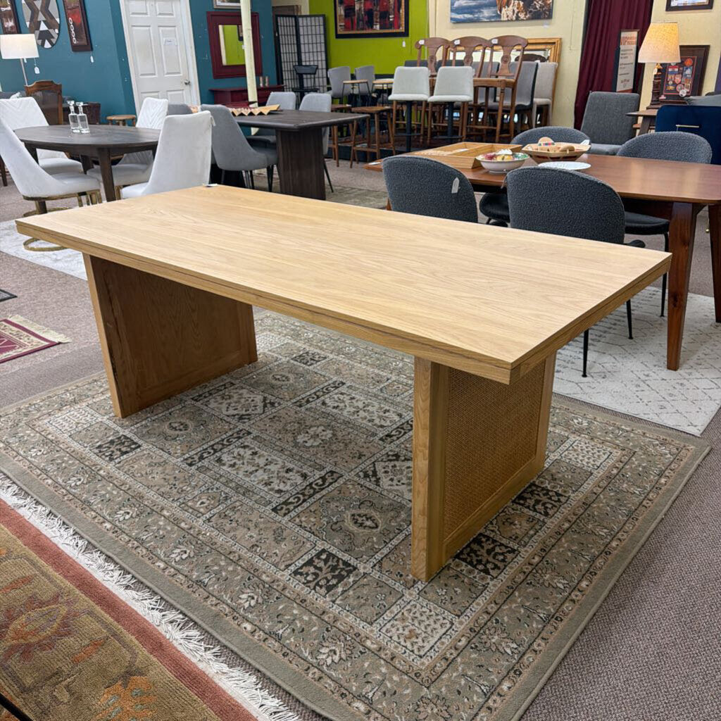 Wooden dining table in a showroom with chairs and other furniture.