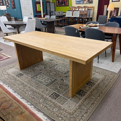Wooden dining table in a showroom with chairs and other furniture.