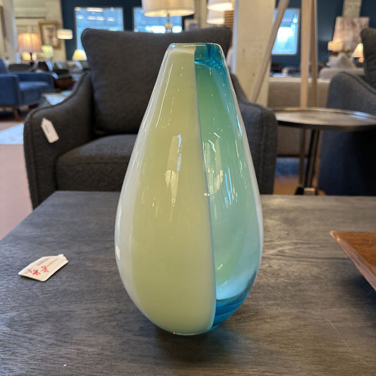 Glass vase with green and blue gradient on a table in a furniture store