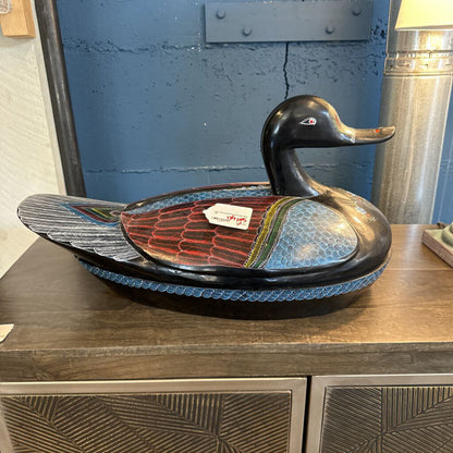 Decorative duck-shaped bowl on a wooden surface with a blue wall in the background