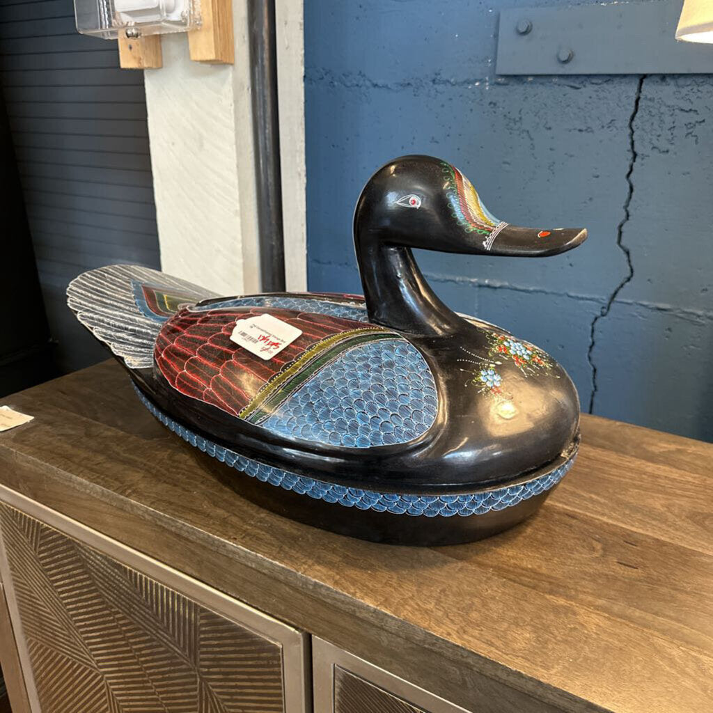 Decorative duck sculpture on a wooden surface with a blue wall in the background