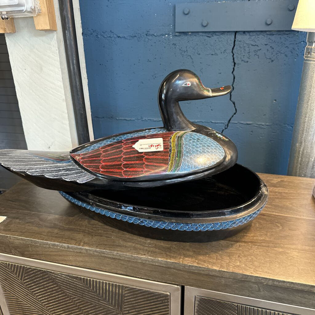 Decorative duck-shaped bowl on a wooden surface with a blue wall in the background