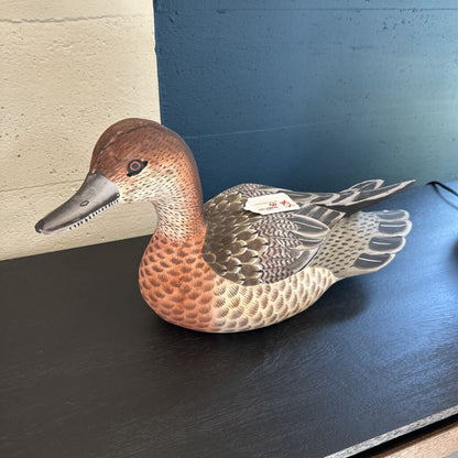 Duck decoy on a dark surface with a neutral background