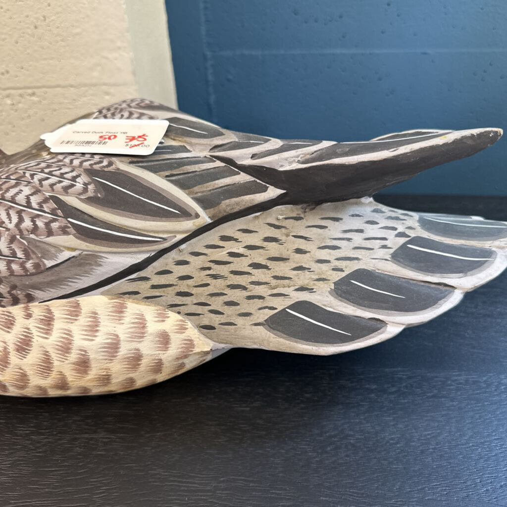 Close-up of a wooden duck decoy with a tag on a blue surface