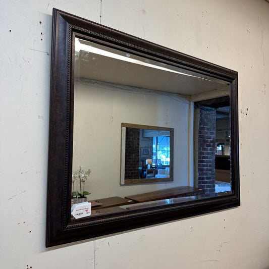 Large black-framed mirror on a white wall
