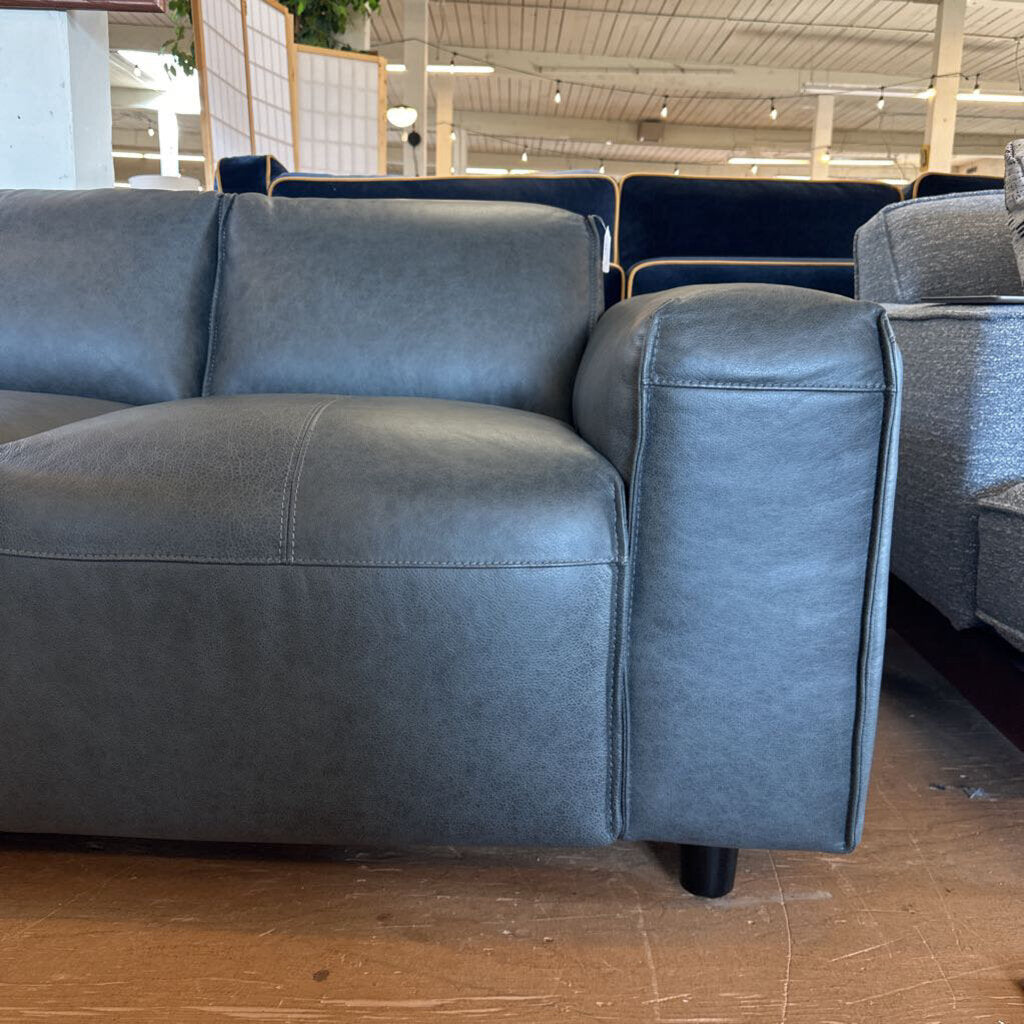 Gray sofa in a warehouse setting with other furniture in the background