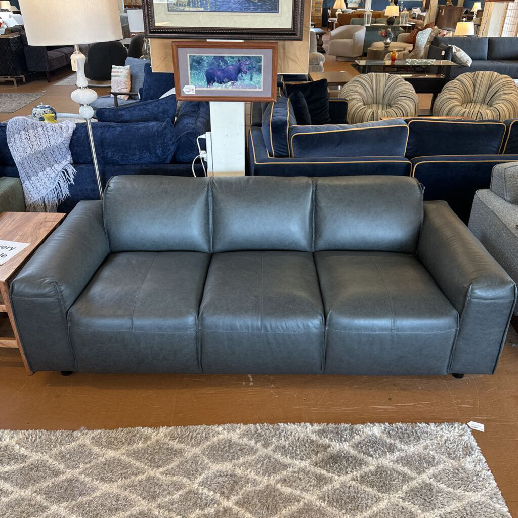 Gray leather sofa in a furniture store with other seating options and decor.