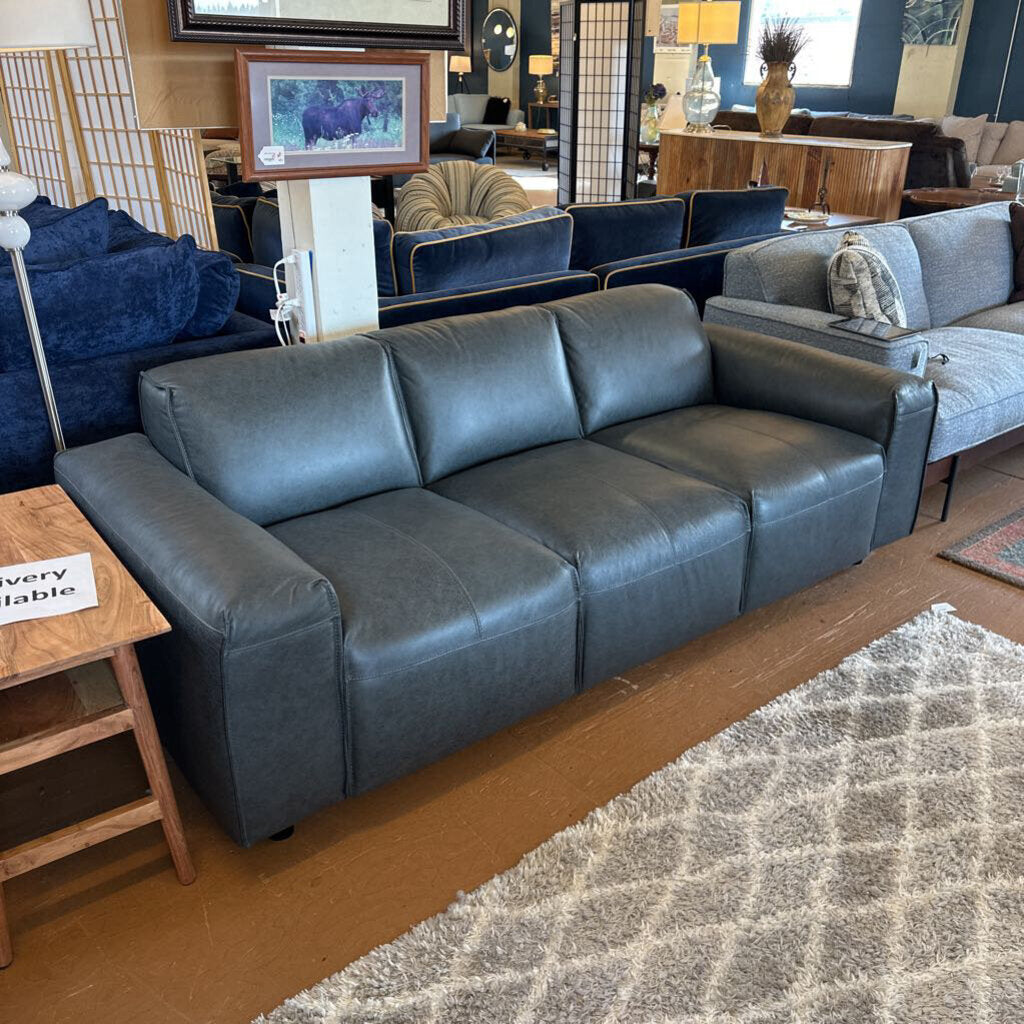 Blue leather sectional sofa in a showroom setting with other furniture and decor items.