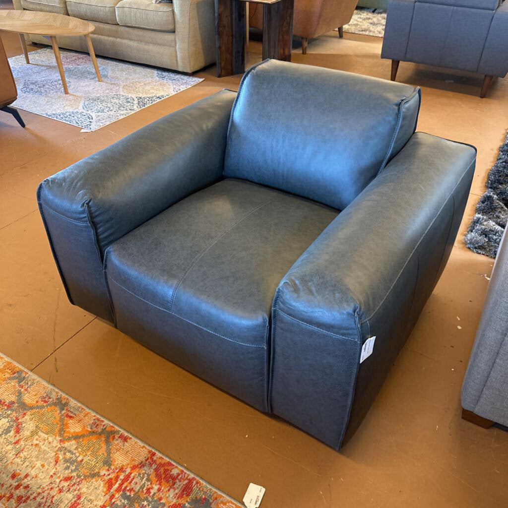 Blue armchair in a room with a patterned rug and furniture.