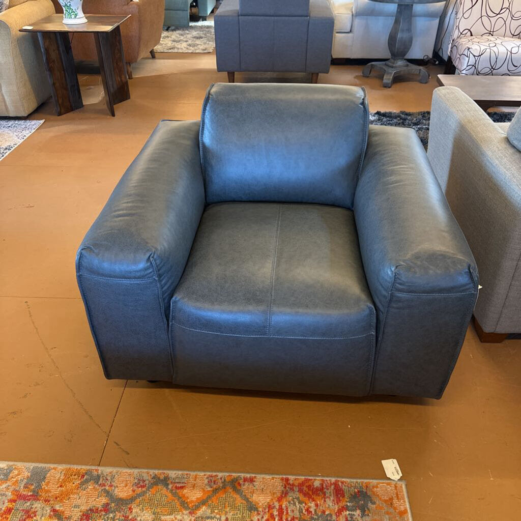 Blue armchair in a room with other furniture and a colorful rug on the floor.