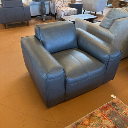 Blue armchair in a showroom setting with other furniture.