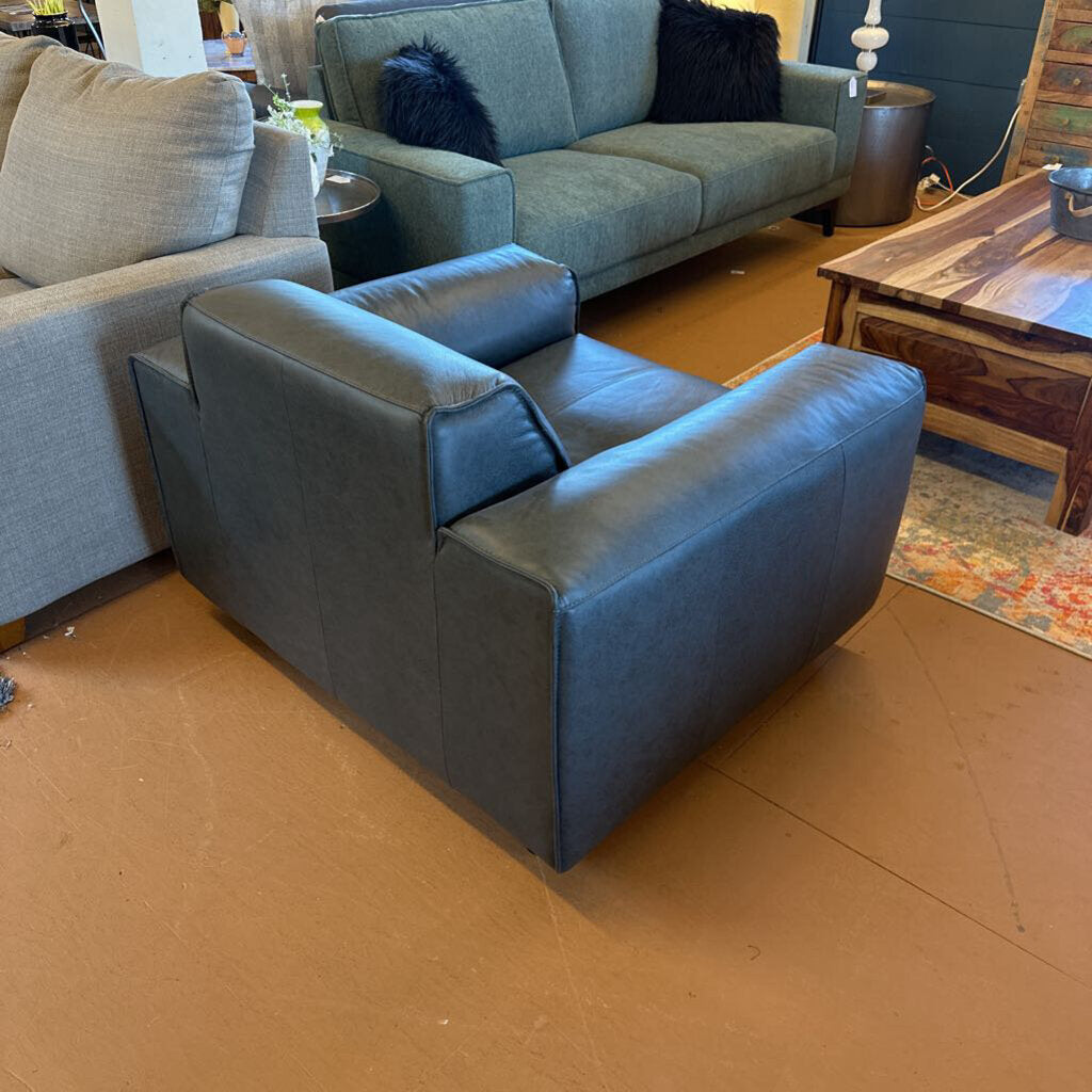 Blue armchair in a living room setting with a gray sofa and wooden coffee table.