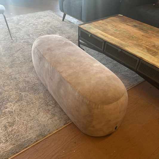Beige ottoman in a living room setting with a wooden coffee table and gray sofa.