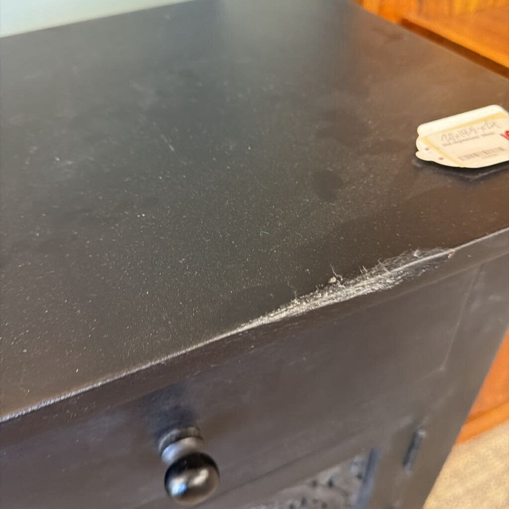 Black cabinet with a small white label on a wooden floor