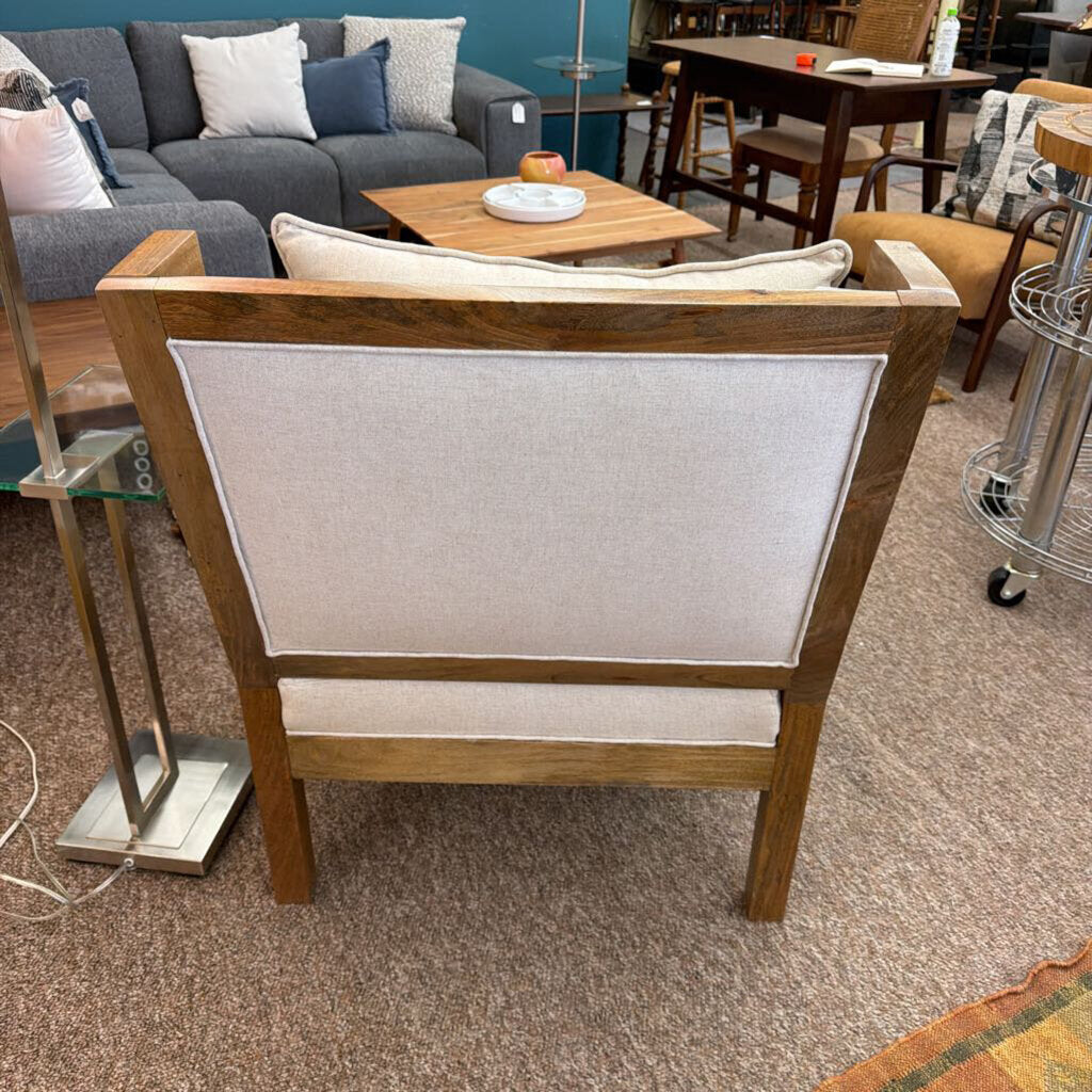 Wooden chair with a white cushion in a room with furniture and decor.