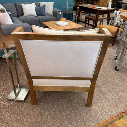 Wooden chair with a white cushion in a room with furniture and decor.