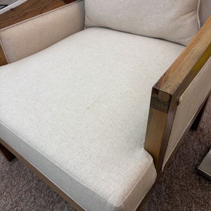 Beige armchair with wooden frame on a carpeted floor