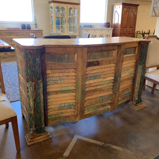 Wooden reception desk in a room with chairs and a rug.