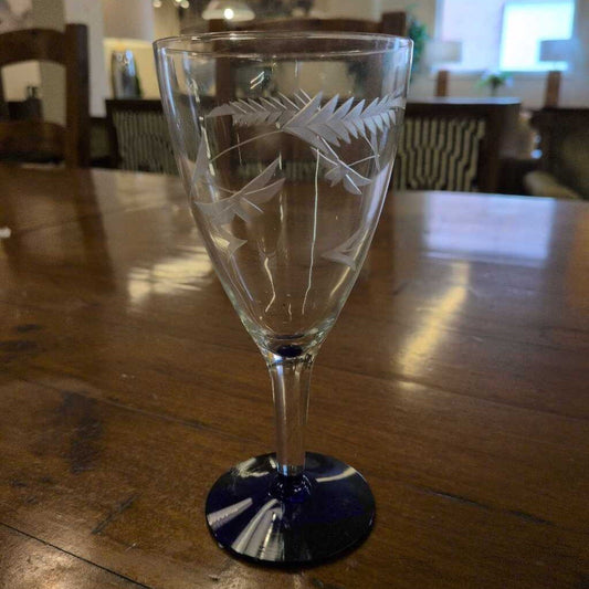 Etched glass goblet on a wooden table with a blurred background