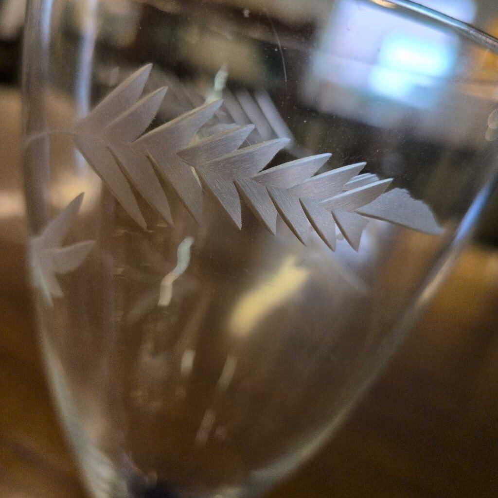 Clear glass with white leaf-like etching on a blurred background