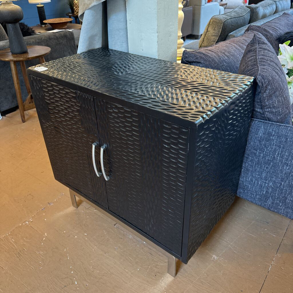 Black woven cabinet with textured surface in a room with furniture
