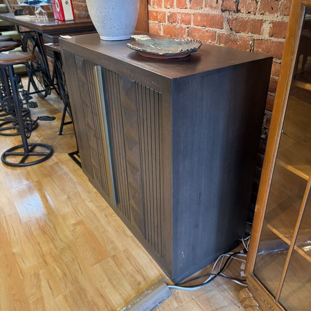 Dark wooden console table with decorative items against a brick wall in a casual setting.