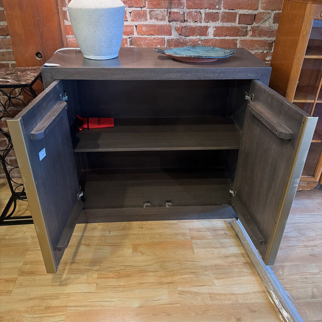 Open cabinet with shelves against a brick wall.