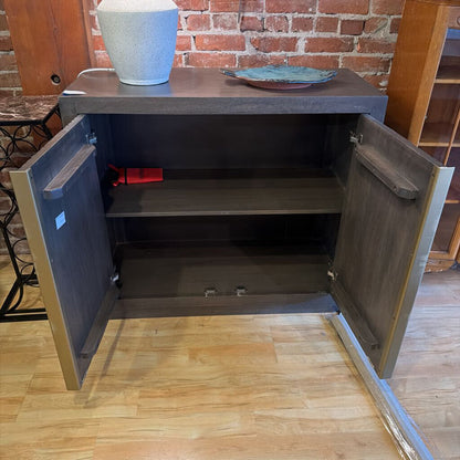 Open cabinet with shelves against a brick wall.
