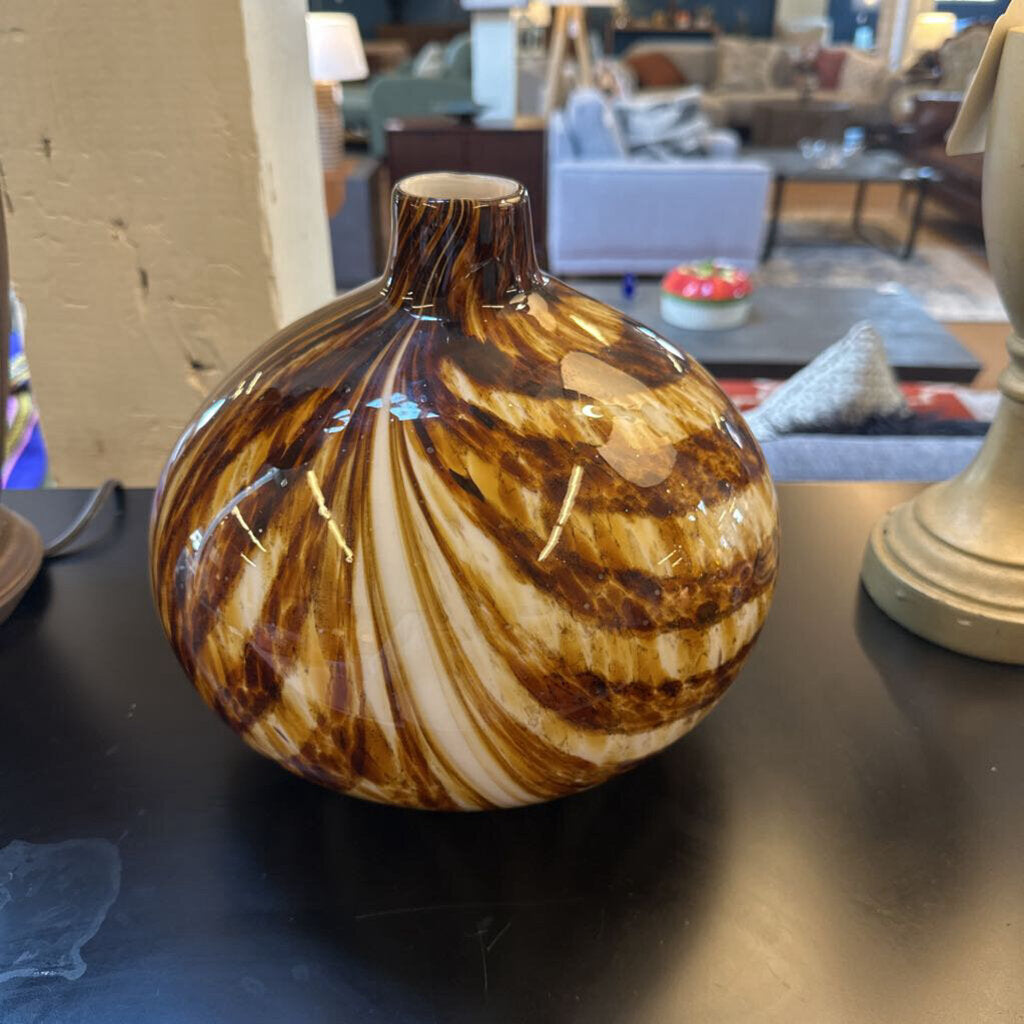 Decorative brown and white vase on a table with a blurred indoor setting