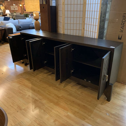 Dark wooden sideboard with open doors in a room with furniture and decor.