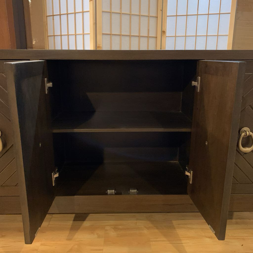 Wooden cabinet with open doors in a room with wooden flooring and a window with blinds.
