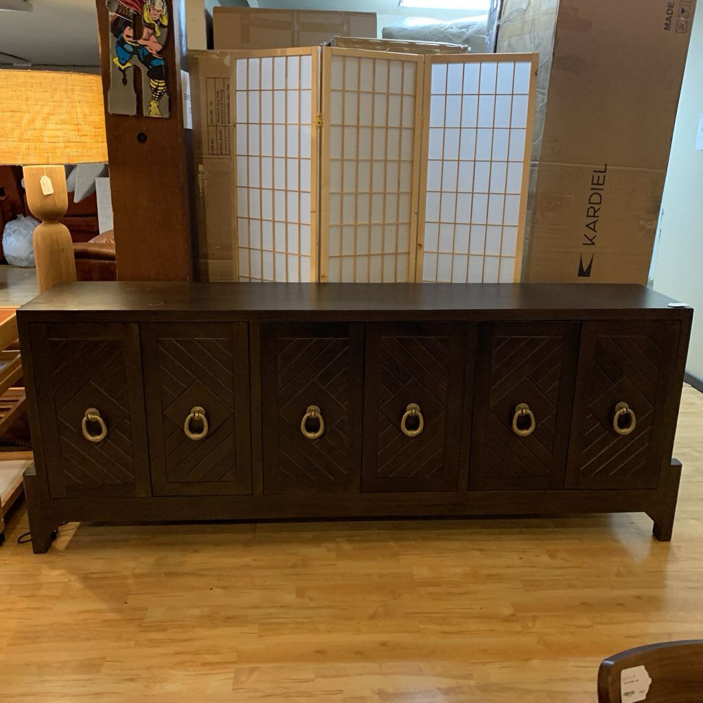 Dark wooden sideboard with decorative handles in a room with cardboard boxes and a lamp.