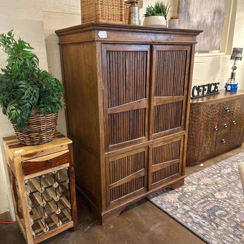 Wooden cabinet with a smaller wooden side table and potted plant in a room setting.