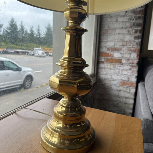 Brass lamp on a wooden surface with a window and outdoor view in the background