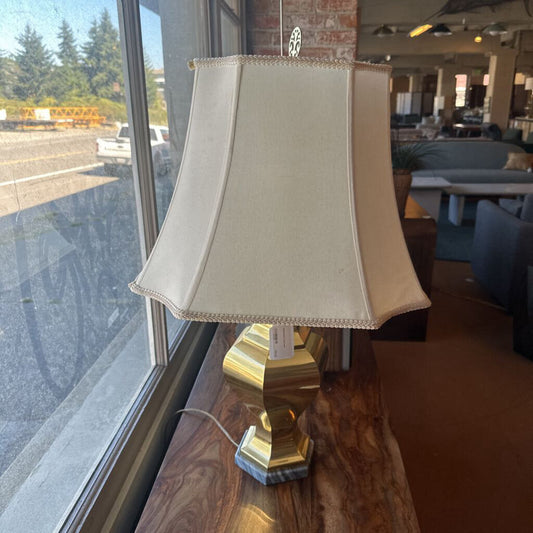 Lamp with beige shade on a wooden table near a window