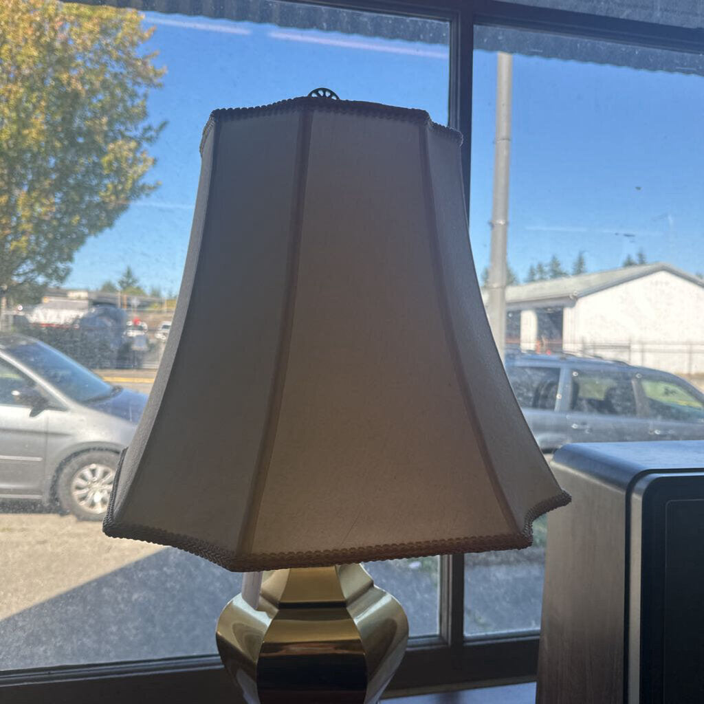 Lamp with a beige shade on a windowsill with cars and trees outside