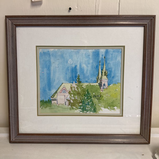 Framed watercolor painting of a landscape with a church and trees.