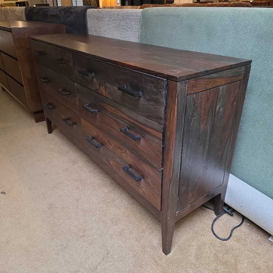 Dark wooden dresser with multiple drawers in a room setting.