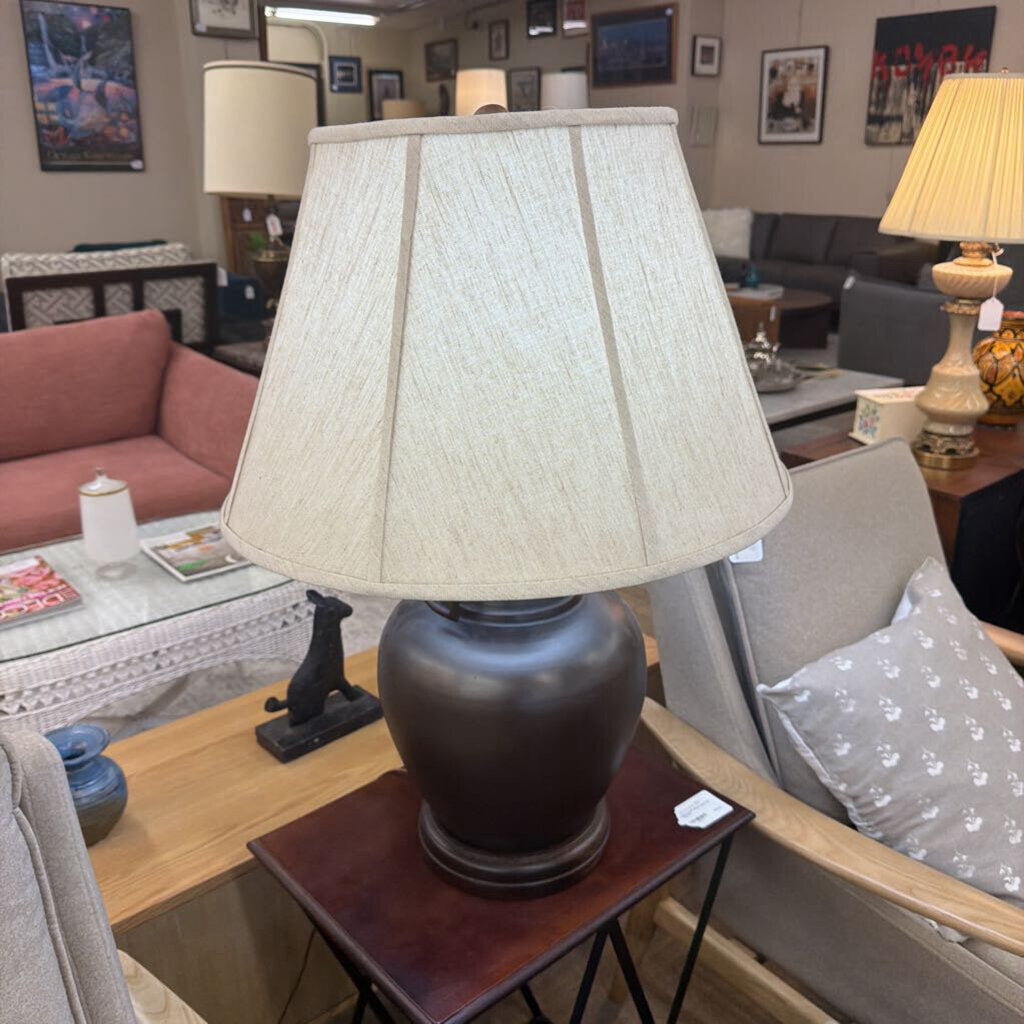 Lamp on a table in a living room setting with furniture and decor.