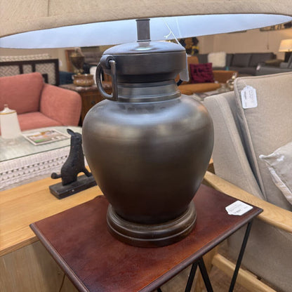 Decorative urn on a wooden table with a blurred background of furniture and decor items.
