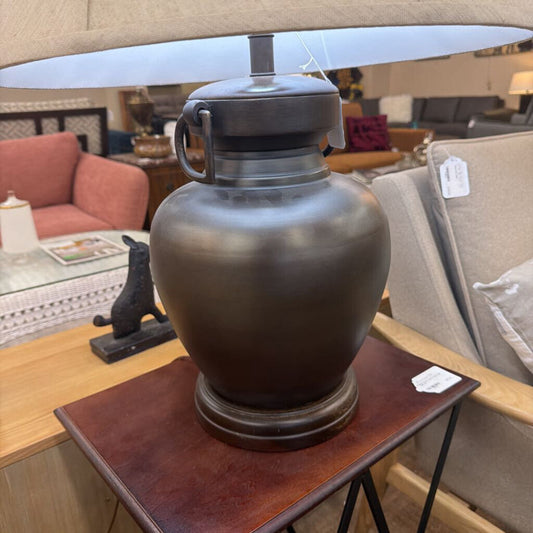 Decorative urn on a wooden table with a blurred background of furniture and decor items.