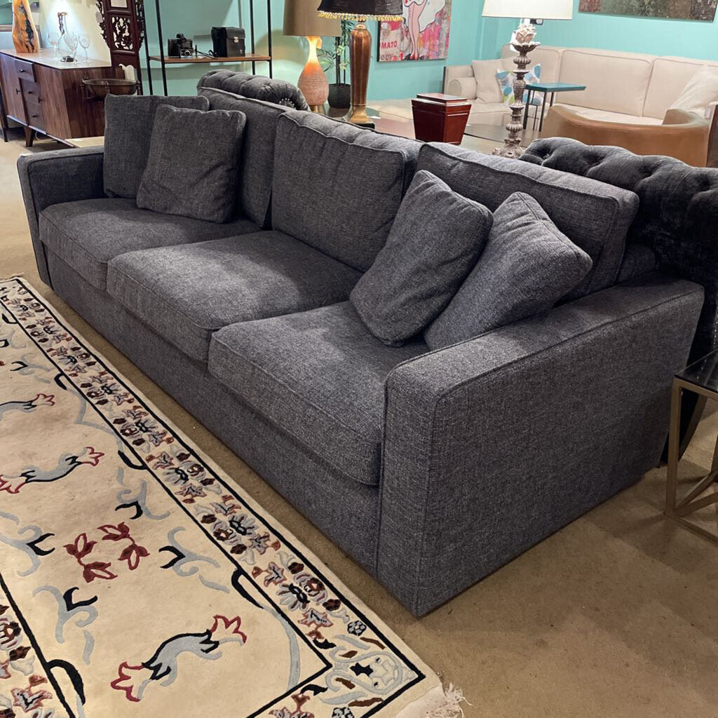 Gray sectional sofa in a living room setting with a patterned rug.