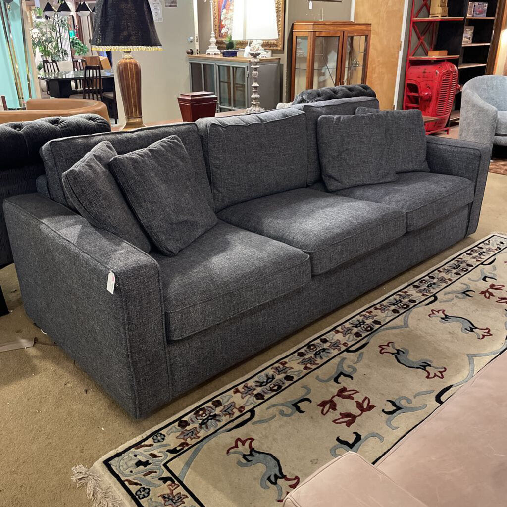 Gray sectional sofa in a showroom setting with other furniture.