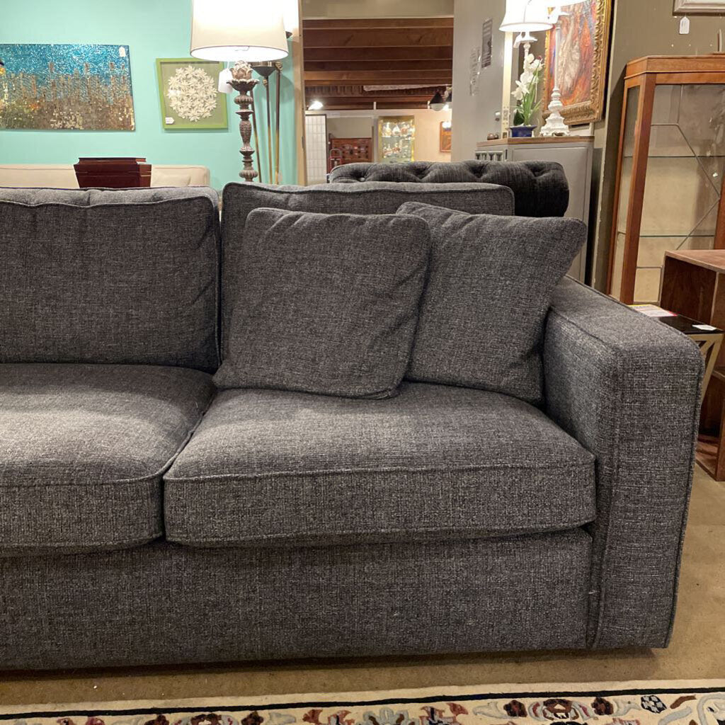 Gray sofa with cushions in a room with furniture and decor.